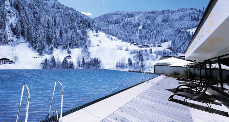 Vanuit de infinity-pool in Das SeeMOUNT Active Nature Resort heb je prachtig uitzicht over besneeuwde bergen van See. © Das SeeMOUNT