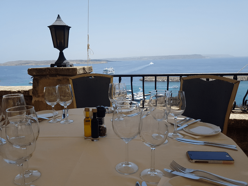 Vanaf het terras van restaurant Country Terrace net boven de haven van Mgarr heb je uitzicht over het Gozo-kanaal, Comino en Malta in de verte. © Nico van Dijk