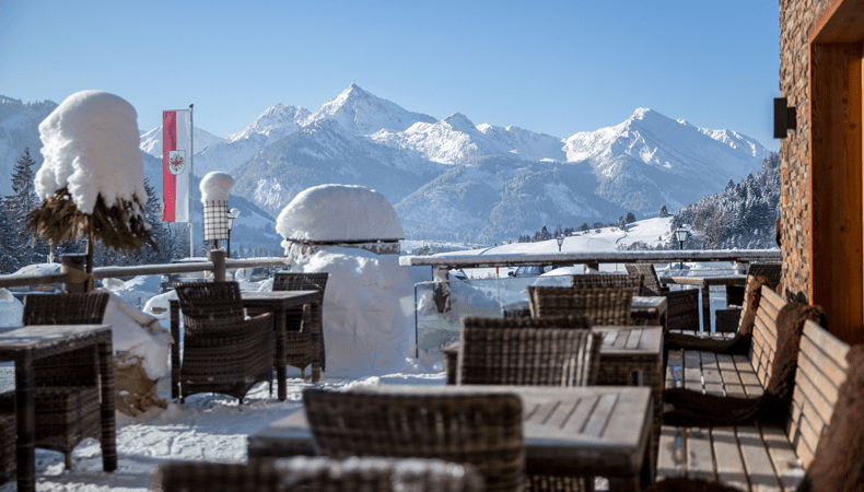Vanaf het besneeuwde terras van Hotel Bergblick kun je genieten van het uitzicht over het Tannheimer Tal. © Hotel Bergblick
